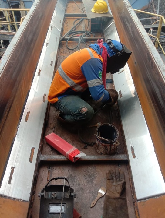 Pekerja PT Sarindo Utama Teknik melakukan welding dan pemasangan lining chute conveyor di area PT Bukit Menjangan Lestari.
